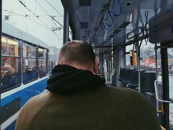 Rear view of man looking through train window