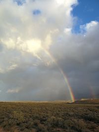 Scenic view of rainbow over field against sky