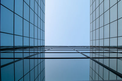 Low angle view of glass building against blue sky