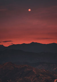 Scenic view of silhouette mountains against orange sky