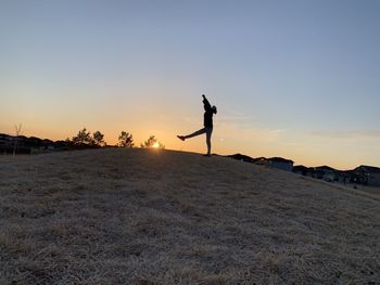 Silhouette man standing on street against sky during sunset