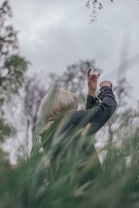 Woman standing amidst grass against sky