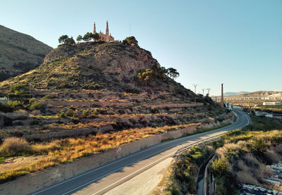 Road leading towards mountain against clear sky