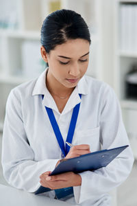 Side view of young businesswoman using mobile phone in office