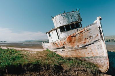 Abandoned boat on beach against sky