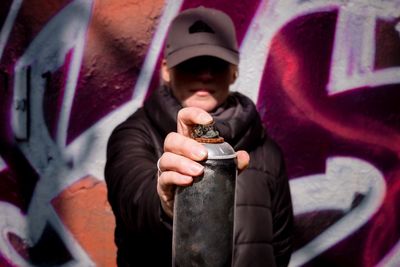 Woman holding aerosol can against graffiti wall