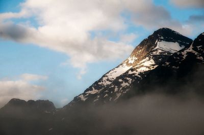 Snow covered mountains against cloudy sky