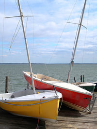 Sailboats moored on sea against sky