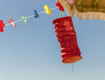 Low angle view of flags hanging against clear blue sky