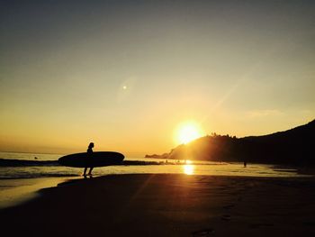 Silhouette person standing on beach against sky during sunset