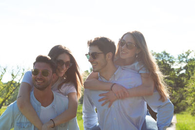 Group of young friends walking in a park while smiling - happy young group of friends