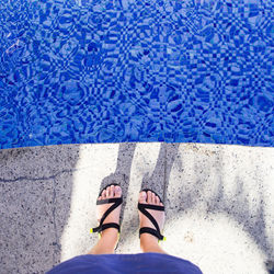 Low section of woman standing by swimming pool