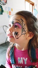 Close-up of girl with tattoo on face at home