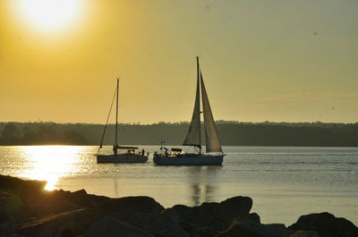 Sailboat sailing on sea against sky during sunset