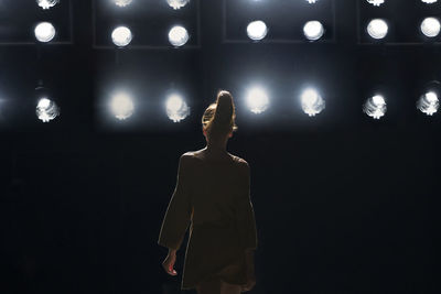 Rear view of woman standing against illuminated lights