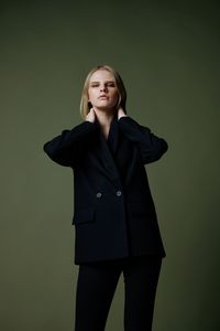 Portrait of young woman standing against gray background