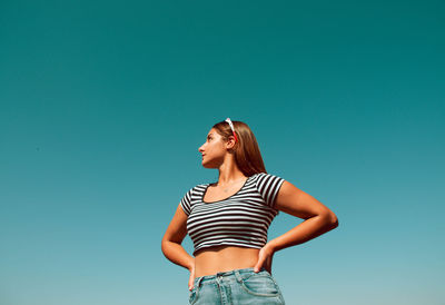 Low angle view of woman standing against blue sky