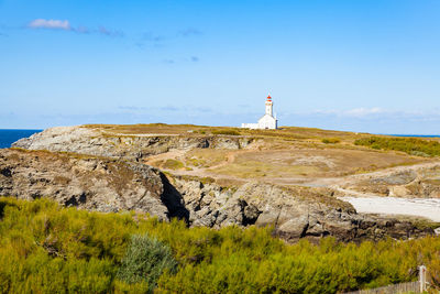 Lighthouse on rock against sky