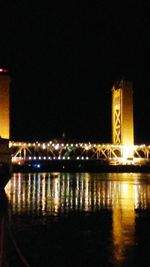 Illuminated bridge over river at night