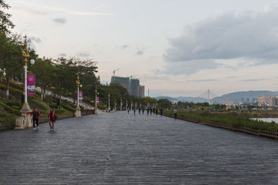 People walking on bridge in city against sky