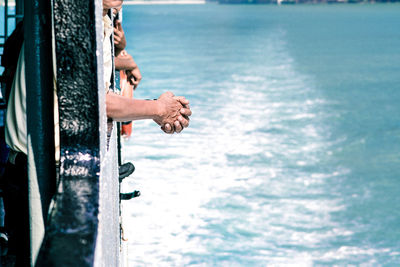 Rear view of man skateboarding on sea against sky