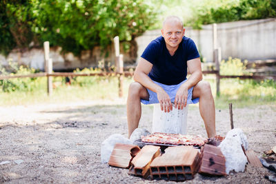 Portrait of man preparing food on barbecue grill in yard