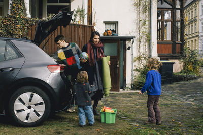 Family loading stuff in electric car while preparing for picnic