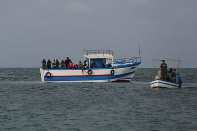 People on boat sailing in sea against sky