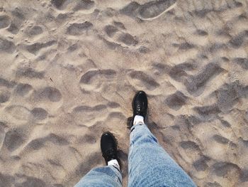 Low section of man standing on sand