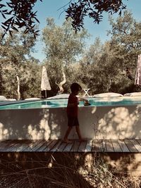 Boy in swimming pool against trees