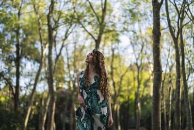 Woman standing amidst trees in forest