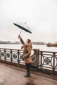 Rear view of woman standing by railing during rainy season