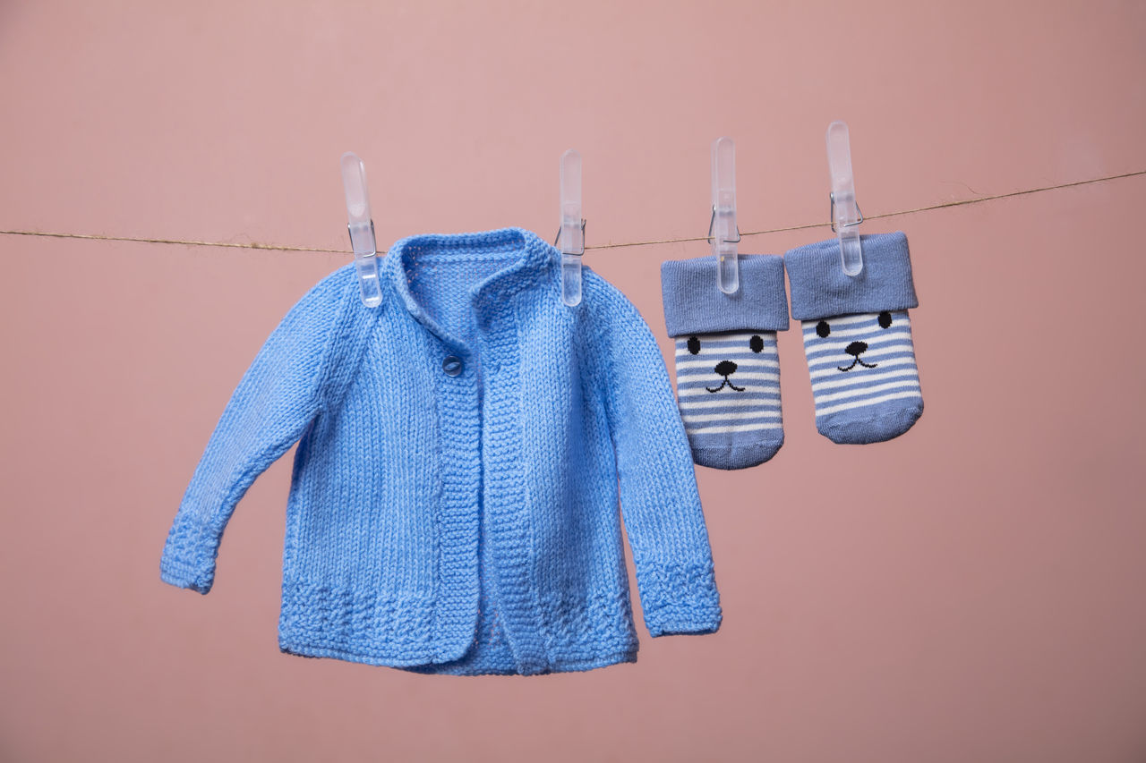 CLOSE-UP OF CLOTHES DRYING AGAINST WHITE WALL