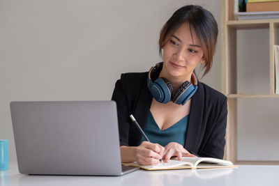 Portrait of young woman using phone while sitting on table