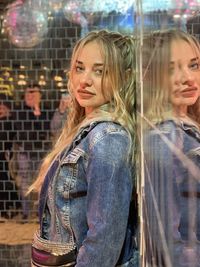 Portrait of beautiful woman leaning on glass wall