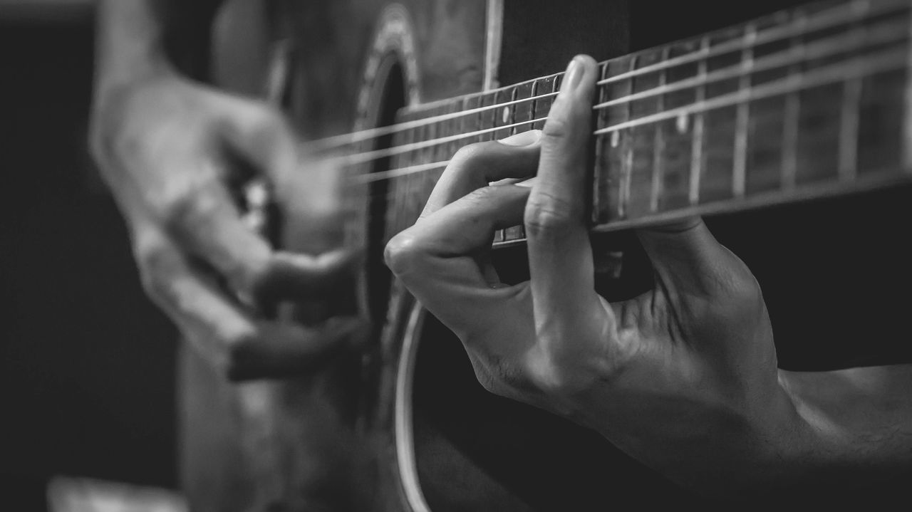 CLOSE-UP OF MAN PLAYING GUITAR AT CAMERA