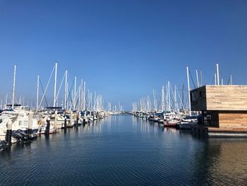 Sailboats moored in harbor against clear blue sky