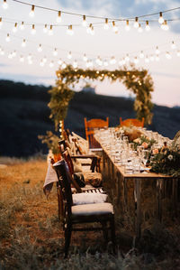 Chairs and tables on table against sky at dusk