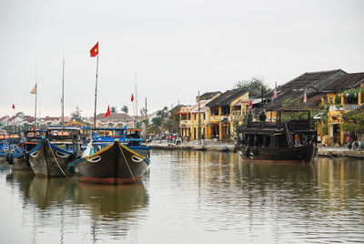 Boats moored at harbor against clear sky