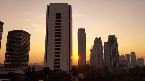 Modern buildings against sky during sunset