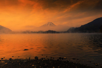 Scenic view of lake against orange sky