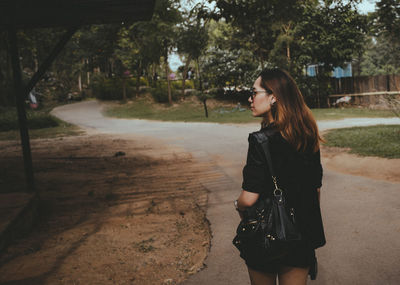 Young woman standing against trees