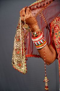 Midsection of bride in traditional clothing over gray background