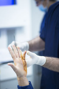 Close-up of surgeon stitching patient hand in operating room