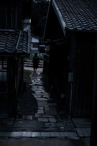 Rear view of man walking on footpath amidst buildings