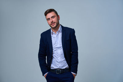 Portrait of young man standing against gray background