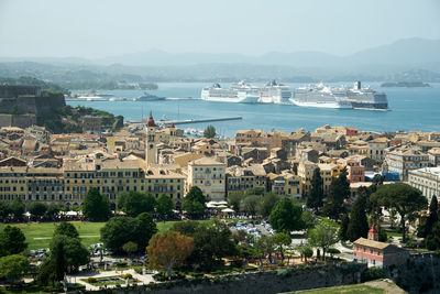 Aerial view of buildings by sea against sky during sunny day