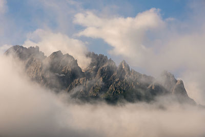 Smoke emitting from mountain against sky