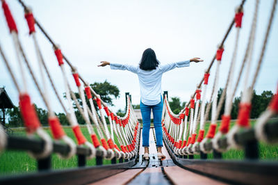 Rear view of woman standing on bridge against sky