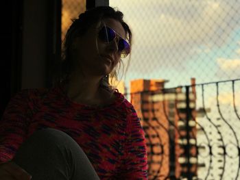 Young woman looking away while sitting outdoors